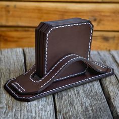 a brown leather business card holder with white stitching on the front and back sides