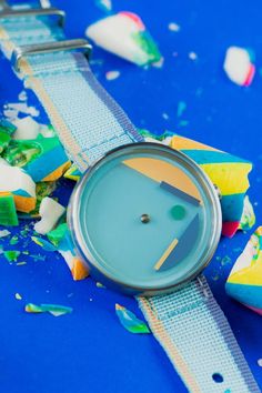 a watch sitting on top of a blue table covered in confetti and sprinkles