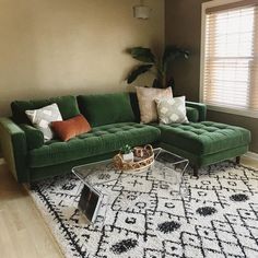 a living room with green couches and pillows on the rug in front of a window