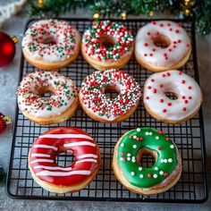 six decorated donuts on a cooling rack next to christmas decorations and baubles