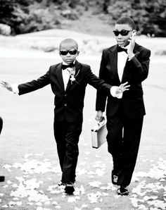 two young men dressed in black suits and sunglasses