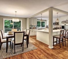 a kitchen and dining room with hardwood floors, white cabinets and an open floor plan