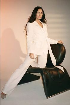 a woman in white is posing on a black chair