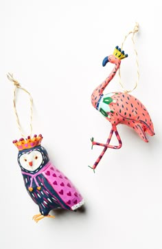 two ornaments made to look like birds with crowns on their heads, one is pink and the other is blue