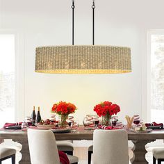 a dining room table with flowers and candles on it, surrounded by two chandeliers hanging from the ceiling