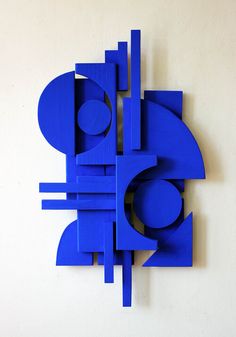 a blue sculpture is on the wall next to a white wall