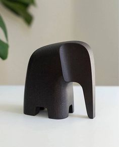 an elephant figurine sitting on top of a table next to a potted plant