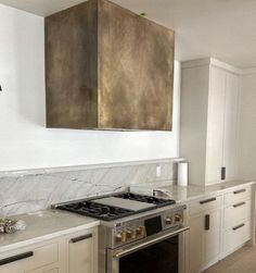 a stove top oven sitting inside of a kitchen next to white cabinets and counter tops