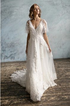 a woman in a white wedding dress standing on a wooden floor with her back to the camera