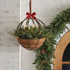 a hanging basket filled with greenery next to a wreath on a door way wall