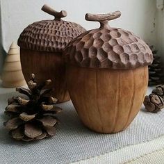 two wooden acorns sitting on top of a table next to pine cones