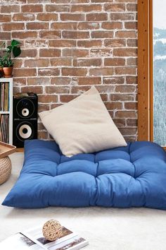 a blue bean bag chair in front of a brick wall with books on the floor