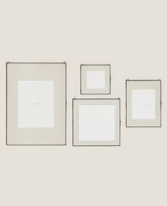 three white square frames hanging on the wall with one empty piece in front of them