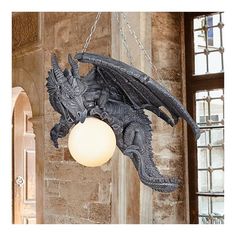 a dragon lamp hanging from a chain in a room with stone walls and stained glass windows