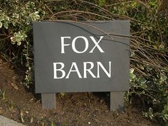 a sign that says fox barn in front of some bushes and trees with no leaves