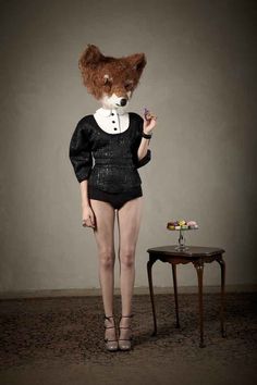 a woman with an animal's head on her head standing next to a table