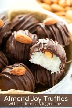 chocolate covered almonds in a bowl with nuts on the side and one half eaten