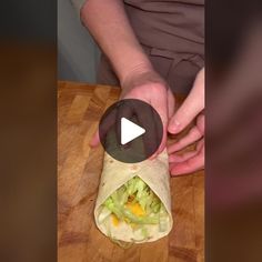 a person is making a burrito with lettuce and cheese