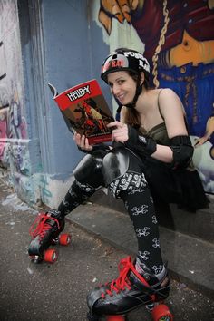 a woman sitting on the ground with roller skates and reading a book in her hand