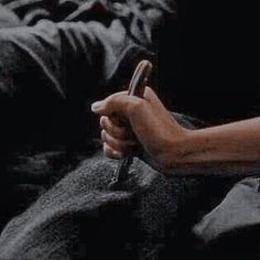 a person holding a cell phone in their hand while sitting on a couch with other people