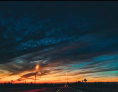 the sun is setting on an empty highway