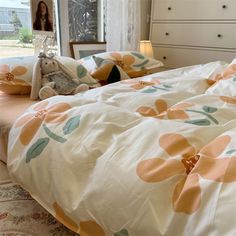 a bed with an orange flowered comforter and two stuffed animals on the pillows