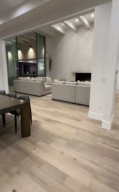 an empty living room with white couches and wood flooring in front of a fireplace