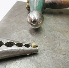 a metal object sitting on top of a table next to a hammer and screwdriver