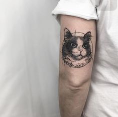 a black and white cat tattoo on the left upper half of the arm, which has a circle around it