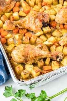 chicken, potatoes and parsley in a baking dish on a white surface with a blue towel