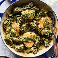 chicken and artichokes in a skillet with a spoon on the side