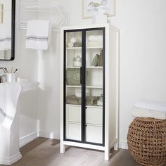 a bathroom with white walls and wood flooring next to a mirror on the wall