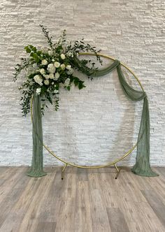 a white and green floral arrangement on a circular stand in front of a brick wall