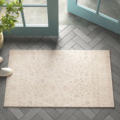 a white rug sitting on top of a floor next to a potted plant