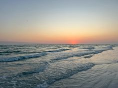 the sun is setting over the water at the beach