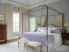 a bedroom with a four poster bed and two chairs in front of the window,