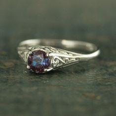 "Alexandrite Ring Filigree Engagement Ring Antique Style Ring Vintage Style Ring June Birthstone Ring June Birthstone Jewelry Silver Filigree \"If you keep on believing, the dream that you wish will come true\" Cinderella sparks memories of glass slippers, fairy god mothers, and dancing until midnight. This is her ring...dainty, intricate and as stunning as can be! A detailed filigree setting securely holds a 5mm Alexandrite of your choice. It is surrounded by intricate vining filigree. The top Purple Intricate Design Promise Ring, Purple Promise Ring With Intricate Design, Elegant Filigree Ring With Birthstone For Wedding, Promise Filigree Ring With Birthstone, Elegant Amethyst Ring For Promise With Intricate Design, White Gold Filigree Ring With Gemstone For Promise, Ornate Promise Ring With Prong Setting, Sterling Silver Amethyst Promise Ring With Intricate Design, Heirloom Style Filigree Ring With Gemstone