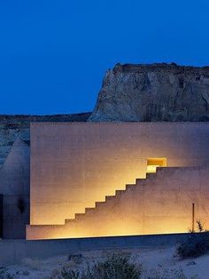 the stairs are lit up at night in front of a large concrete structure with windows