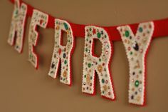 the word happy is spelled with beads and sequins on a red string hanging from a wall