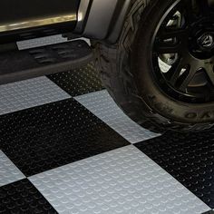 a black and white checkered floor with a tire on the front of a vehicle