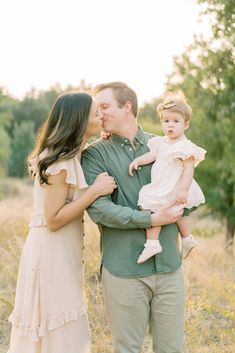 a man and woman kissing while holding a baby