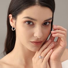 a woman in a white dress holding a cell phone to her ear and looking at the camera