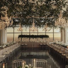 an indoor dining room with chandeliers and tables set for formal function at dusk