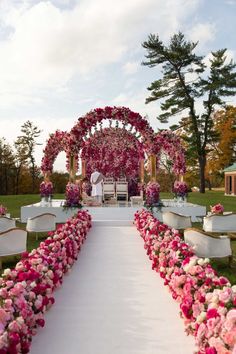 an outdoor ceremony setup with pink and white flowers on the aisle leading to the altar