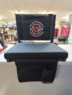 a black bag sitting on top of a counter next to a red and white shirt