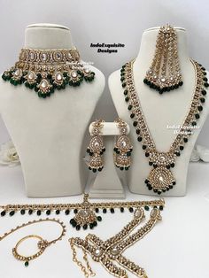 two white mannequins with green and gold jewelry on display next to each other