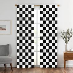 a black and white checkered curtain hanging in front of a window next to a chair