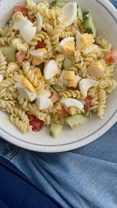 a white bowl filled with pasta and veggies on top of a blue cloth