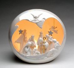 a glass ball with nativity scene in it on a grey surface, showing the birth of jesus and three wise men