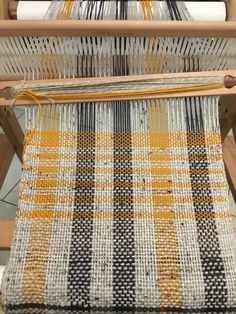 an old weaving machine with yellow and black yarn on it's sides, in the process of being woven